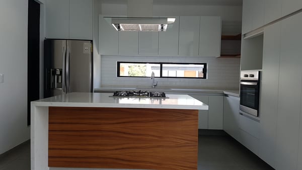 Cocina con isla de frente de madera, refrigerador de acero y horno empotrado.