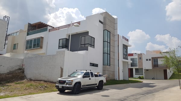 Calle del conjunto residencial con las viviendas en obra y una camioneta estacionada al frente.